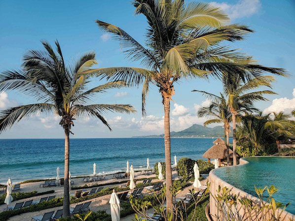 A resort with a pool, lounge chairs, and palm trees.