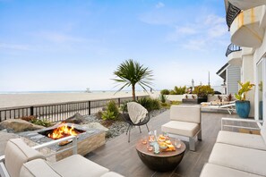 Une terrasse avec un foyer extérieur, des sièges et une vue sur la plage.