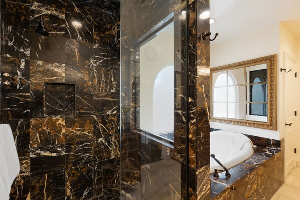 A bathroom with a marble floor, a large mirror, and a bathtub.