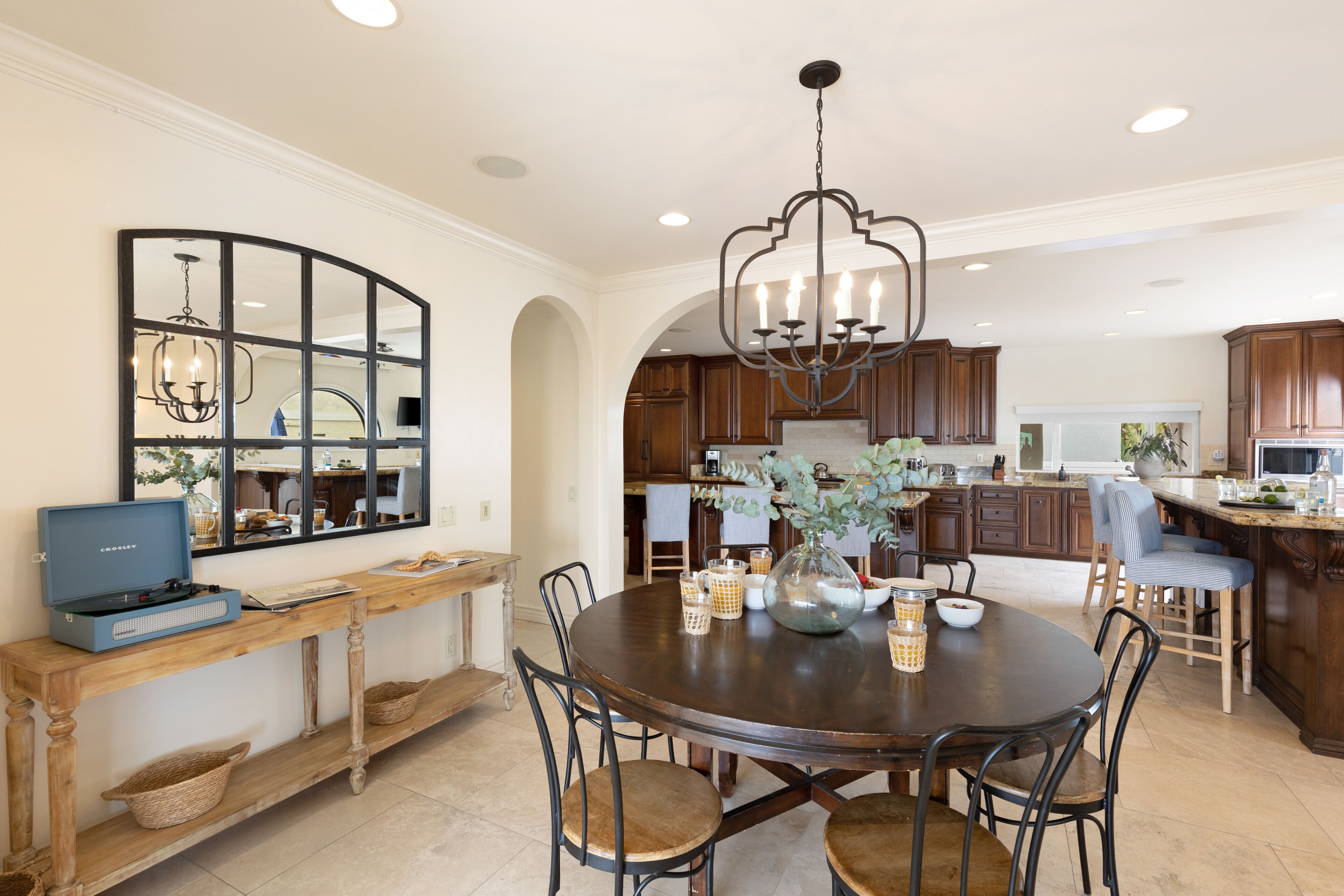 A spacious kitchen with wooden cabinets, a central island, and a dining area with a round table and chairs.