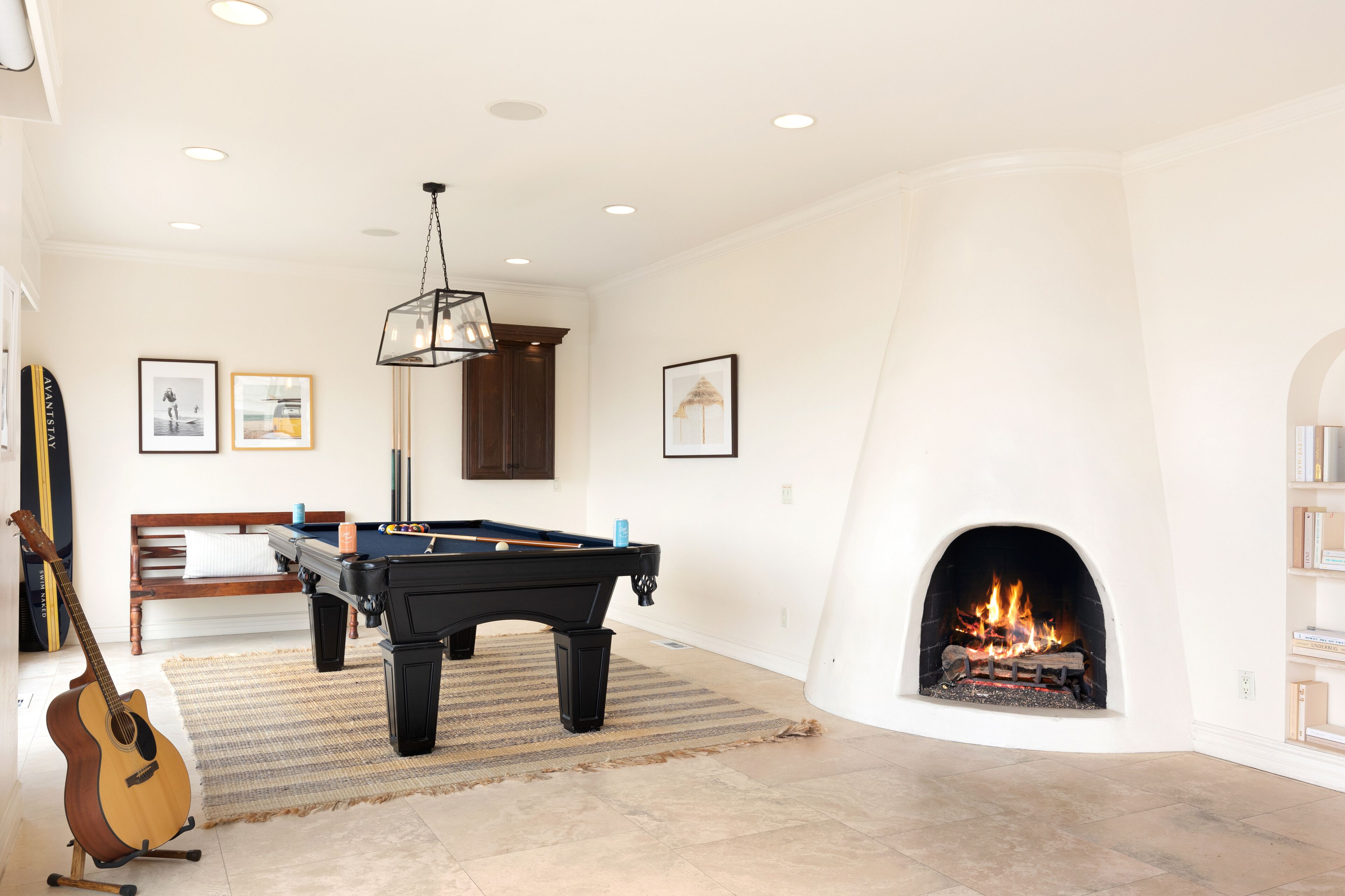 A living room with a pool table, a fireplace, and a guitar.