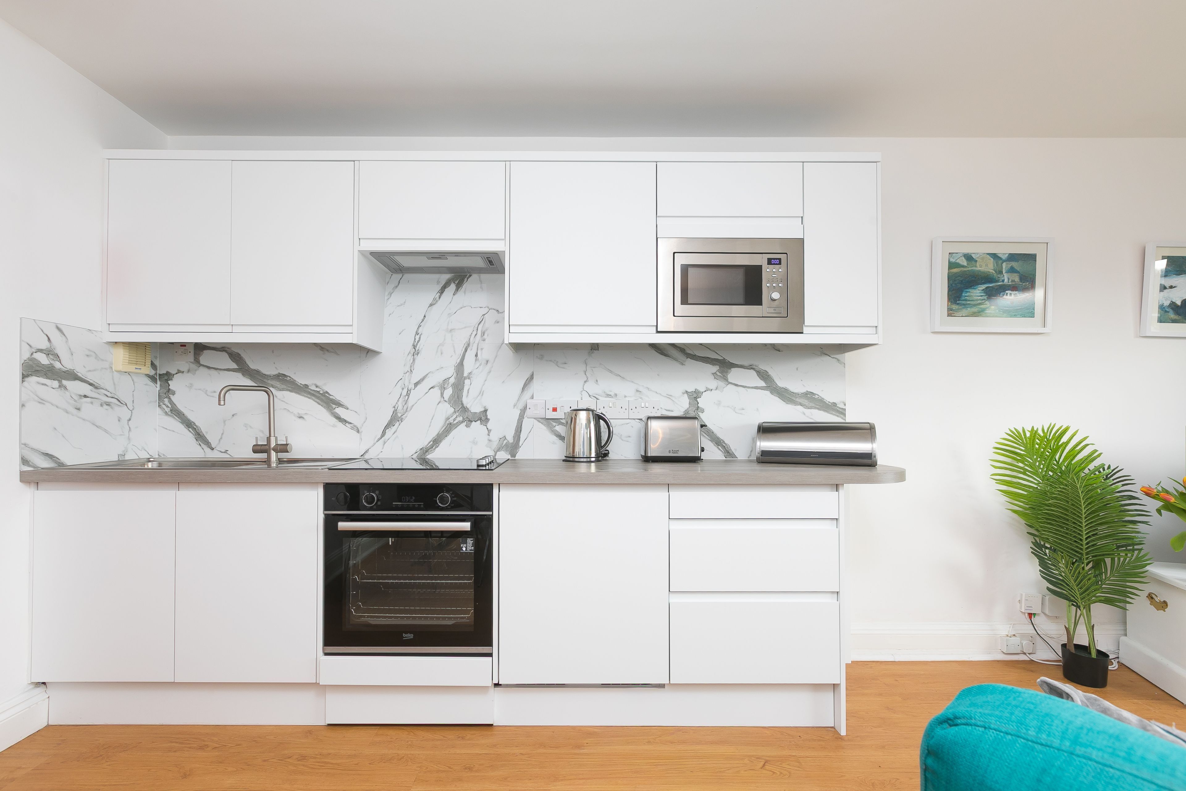 Eine moderne Küche mit weißen Schränken, einem eingebauten Backofen, einer Mikrowelle und einem Toaster.