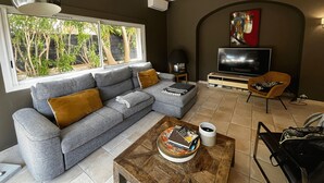 Una sala de estar con un sofá gris, una mesa de centro de madera, un televisor y una silla.