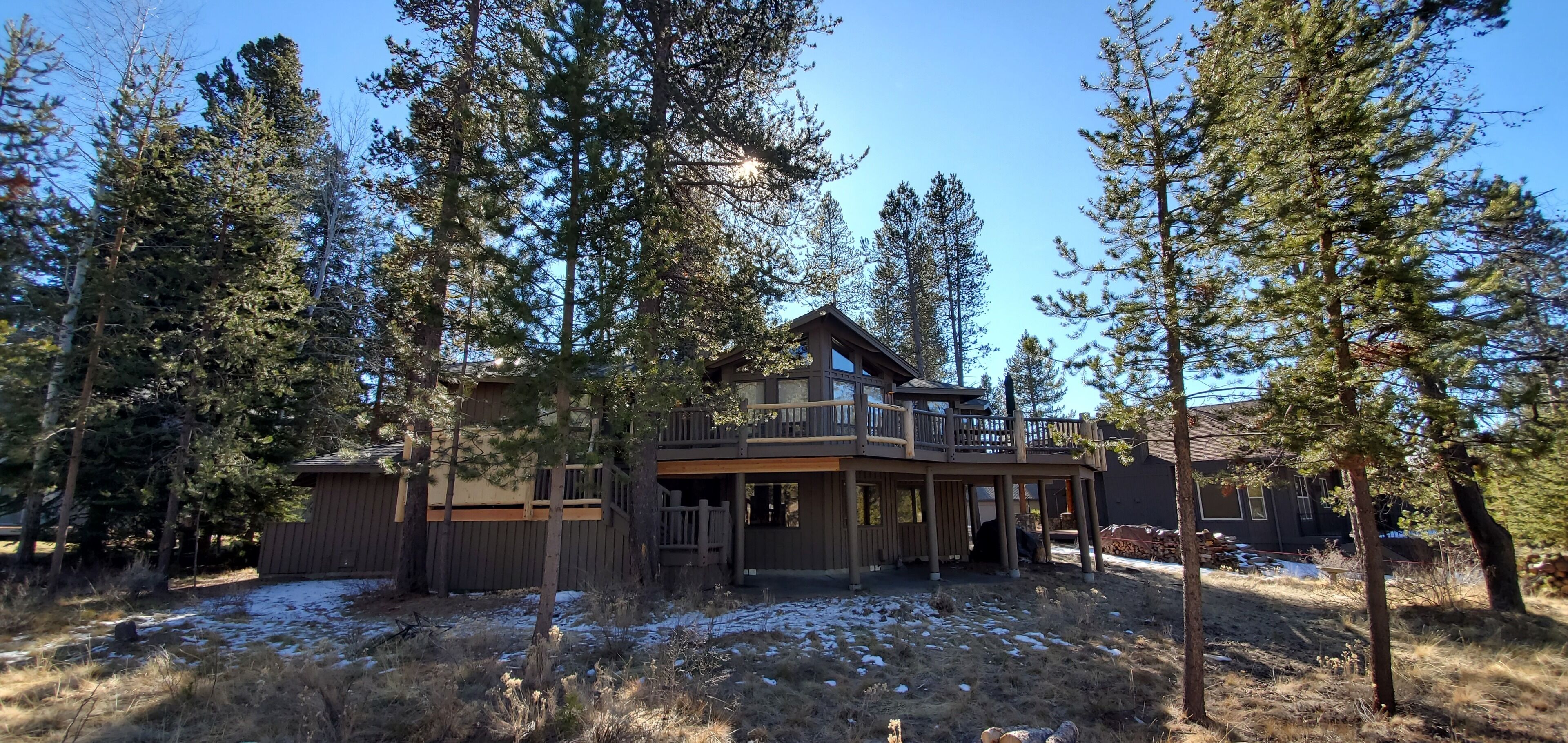 A cabin with a deck and a large window overlooking a forested area.