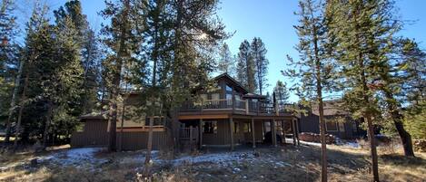 A cabin with a deck and a large window overlooking a forested area.