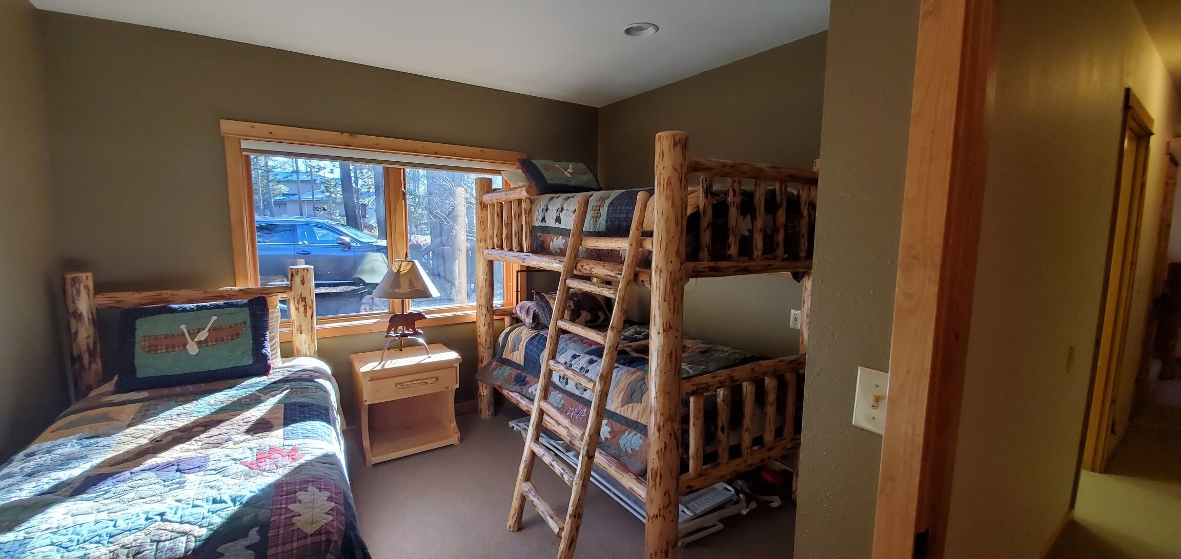 A bunk bed room with a window, a desk, and a chair.