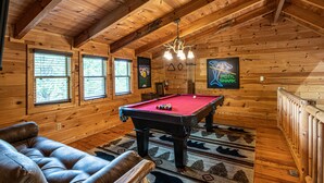 Ein Holzinterieur mit Billardtisch, Ledersofa und einer Kandelaber.