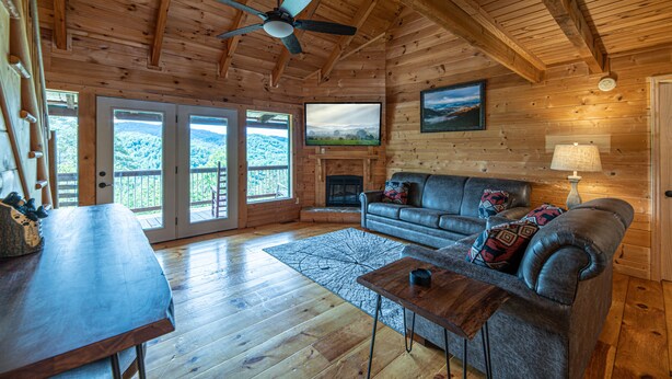 Ein Holzblockhaus-Interieur mit Kamin, Ledersofa und Esstisch.