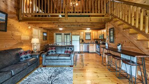 Ein Holzblockhaus mit Wohnzimmer, Küche und einer Treppe.