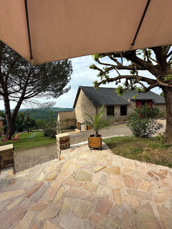 A stone patio with outdoor seating, a stone building, and a view of the surrounding landscape.