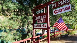 Placa do Pinehurst Resort com uma bandeira americana, indicando um parque de trailers e cabanas.