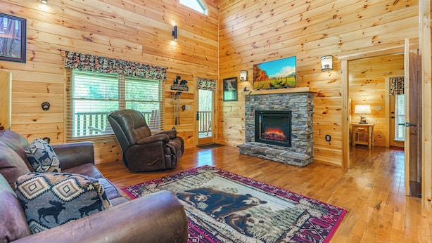 A log cabin interior with a fireplace, leather recliner, and a large rug.