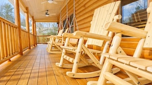 A wooden deck with rocking chairs and ceiling fans.