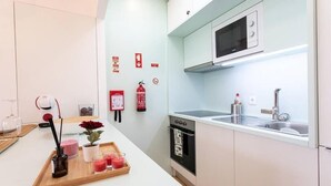 Une cuisine moderne avec des meubles blancs, un four à micro-ondes, un évier et un grille-pain. On peut voir des bougies et un plateau avec des boissons sur le comptoir.