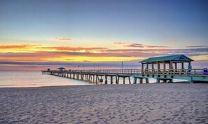A beach with a pier extending into the water, a covered seating area, and a clear sky. - Tropical Paradise Beach Getaway, Villa #1 (Lauderdale-by-the-Sea)