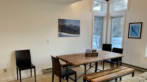 A dining area with a wooden table, four chairs, a bench, and a painting on the wall. - 10th Hole Haystack Golf Course in Wilmington VT - 4 miles from Mt Snow (Wilmington)