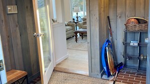 A room with a wooden door leading to a living area, a small table, a blue exercise bike, and a basket with a basketball. - 10th Hole Haystack Golf Course in Wilmington VT - 4 miles from Mt Snow (Wilmington)