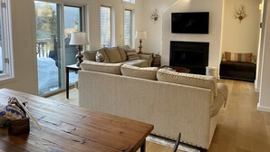 A living room with a sofa, a TV, a fireplace, and a dining table. - 10th Hole Haystack Golf Course in Wilmington VT - 4 miles from Mt Snow (Wilmington)