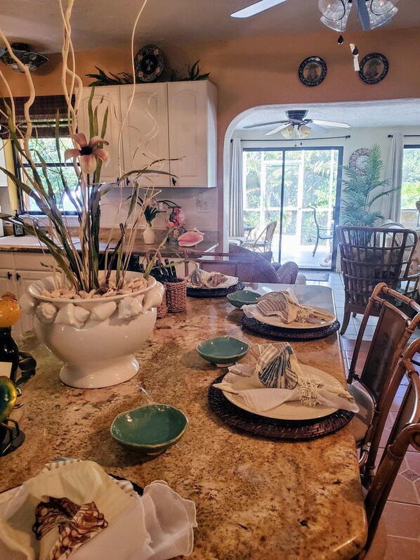 A kitchen with a granite countertop, white cabinets, and a dining area with a table set for four.