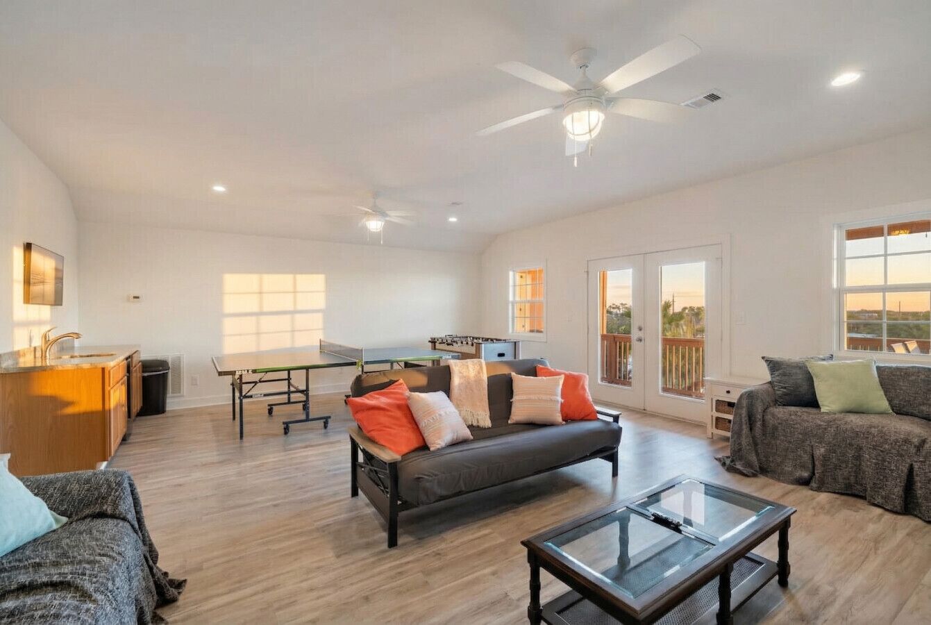 A spacious living room with a sofa, coffee table, and a ping pong table.