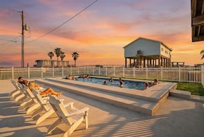 A swimming pool area with lounge chairs and a building in the background. - Spacious Home with Game Room, Deck & Bunk Room (Surfside)