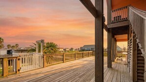 Une terrasse en bois avec une rambarde, un escalier et une vue sur les environs.