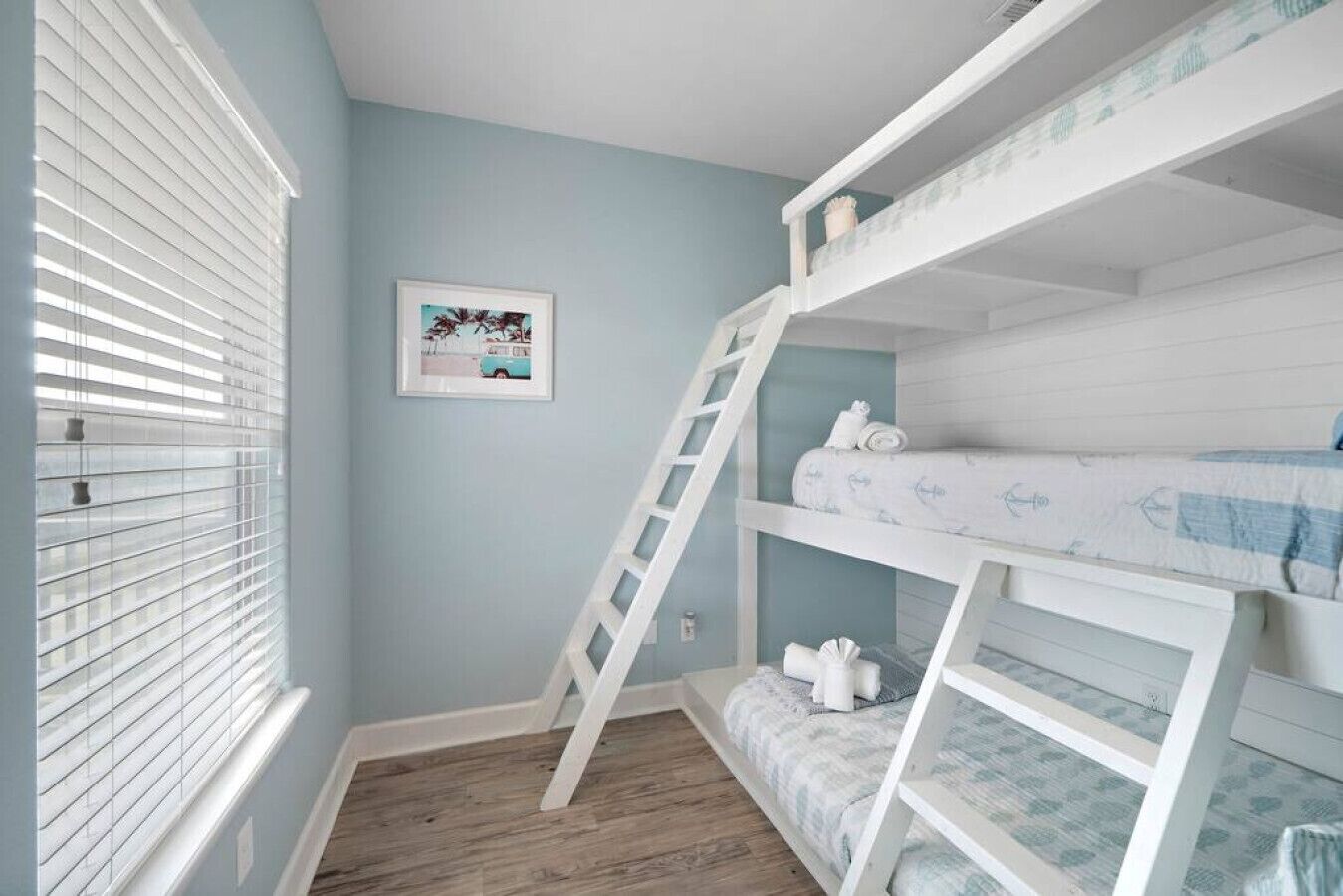 Habitación con literas, una escalera, un cuadro en la pared y una ventana con persianas.