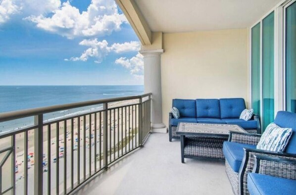 Un balcón con vista al océano, un sofá azul y muebles de mimbre.