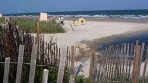 A beach with a wooden fence in the foreground, a clear sky, and a few people in the distance. - Fun In the Sun ~ Ocean Lakes  (Myrtle Beach)