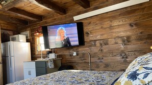 Une chambre confortable, aménagée dans le style d’un chalet, avec un lit, un téléviseur fixé au mur, un réfrigérateur et une petite kitchenette.