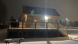 Une cabane en bois avec un toit en métal, une véranda et un escalier menant à l’entrée.