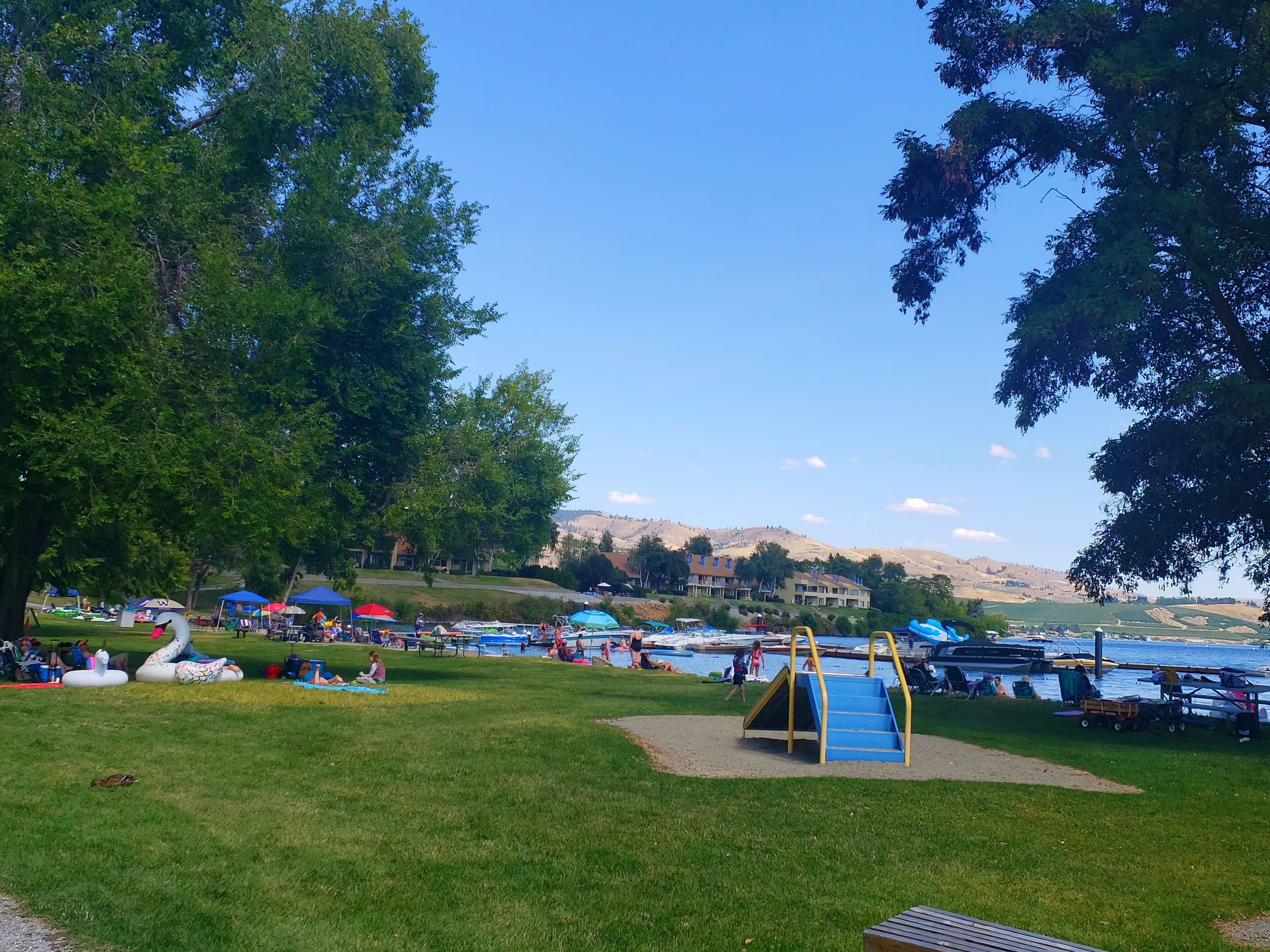 Un parc doté d’une aire de jeux, d’espaces aménagés pour les pique-niques et offrant une vue sur un lac.