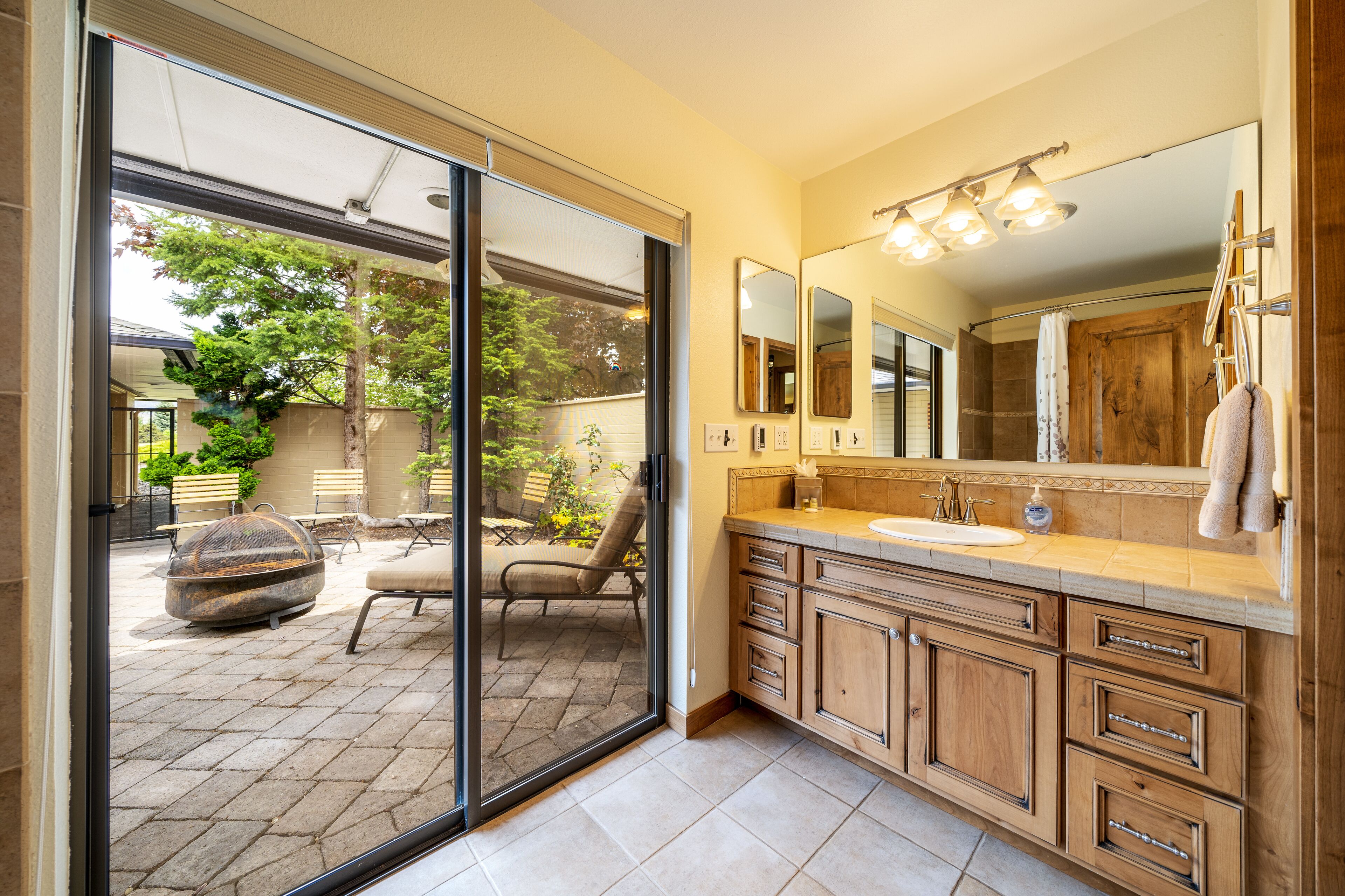 A bathroom with a large mirror, wooden cabinets, and a sink.