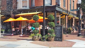 Een terras met tafels en stoelen onder oranje parasols bij een restaurant genaamd South End Buttery.