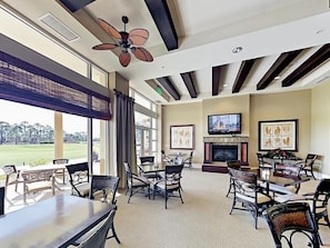 A spacious indoor area with multiple tables and chairs, a fireplace, and a television mounted on the wall.