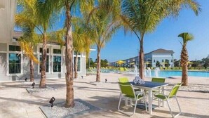 Un área de piscina al aire libre con sillas de descanso, una mesa y palmeras.