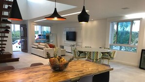 Een moderne keuken met een houten eettafel, grijze stoelen en een fruitschaal.