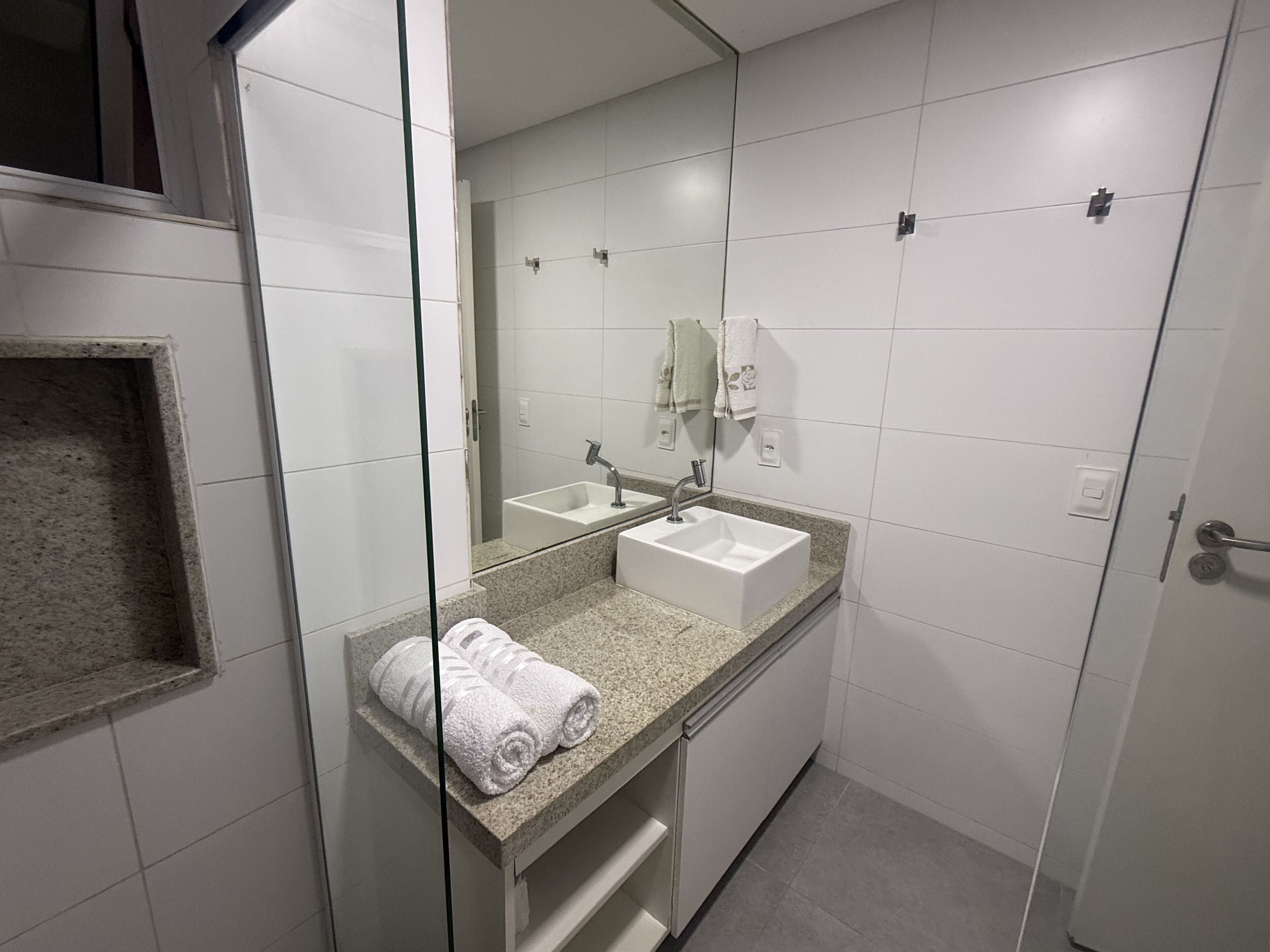 Ein modernes Badezimmer mit Duschkabine aus Glas, einem weißen Waschbecken und einem Spiegel.