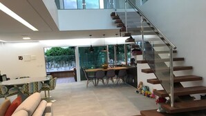 Een moderne woonkamer met een trap, een eethoek en uitzicht op de omgeving.