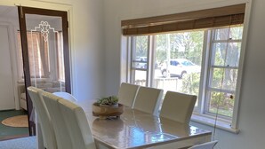 A dining area with a table, chairs, and a window with a view of the outside.