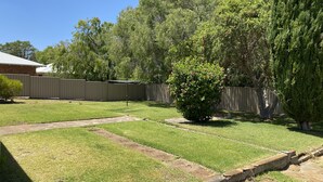A backyard with a lawn, a wooden fence, and a tree.