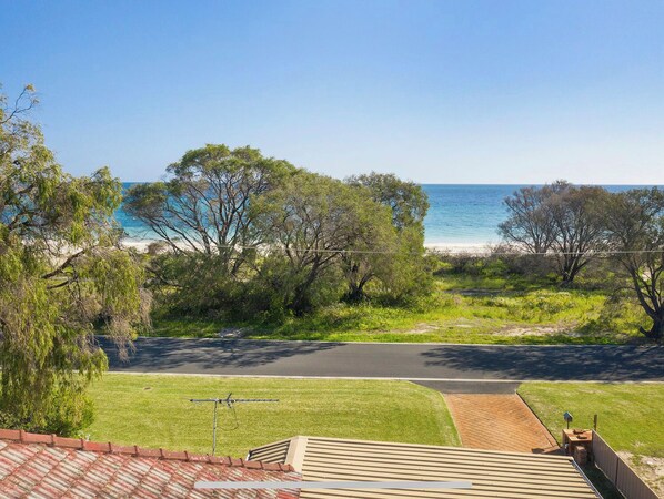 A coastal view with a road leading to the beach, surrounded by trees and a grassy area. - Abbey Beach Oasis (Abbey)