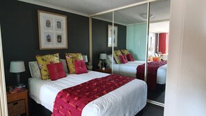 A hotel room with two beds, a large mirror, and a framed picture on the wall. - Oceanview Escape at The Entrance (The Entrance)