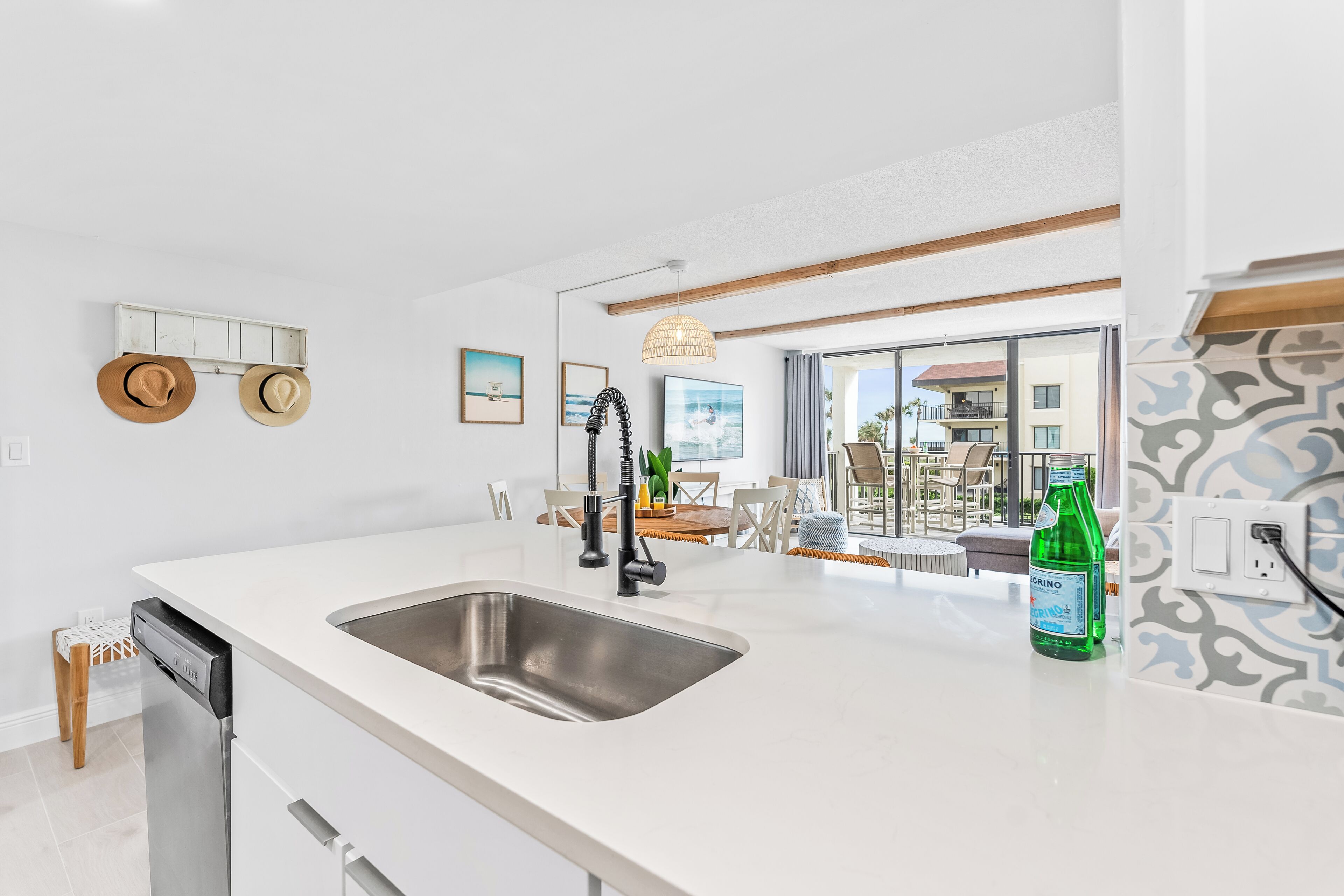 A modern kitchen with a large island, stainless steel sink, and a dining area with a view of the ocean.