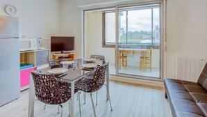 A modern apartment with a dining area, kitchen, and a large sliding glass door leading to a balcony. - Horizon Océan 1 by Interhome (Capbreton)