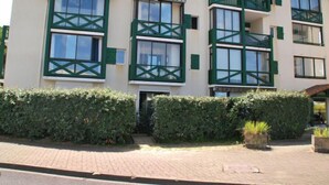 A multi-story building with green-framed windows and balconies, surrounded by well-maintained hedges. - Horizon Océan 1 by Interhome (Capbreton)