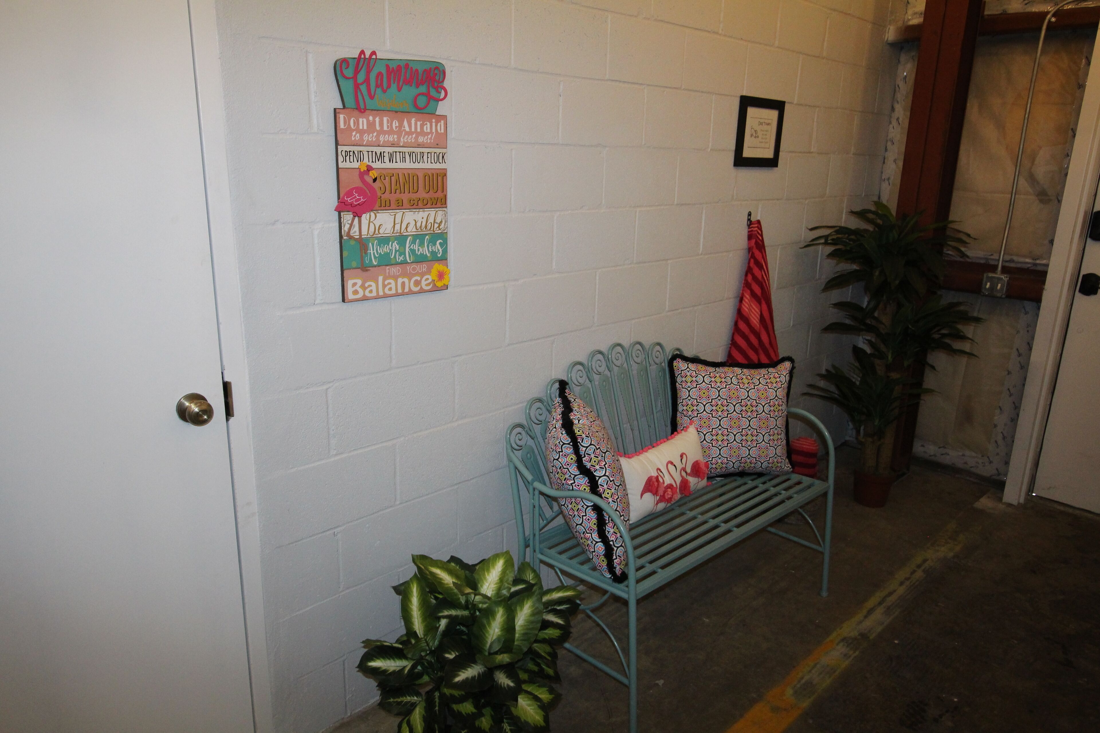 A room with a bench, a potted plant, and motivational wall art.