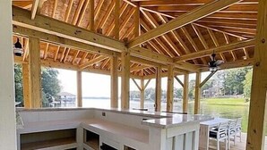 Une terrasse en bois dotée d’un espace cuisine intégré, comprenant un comptoir et des placards.