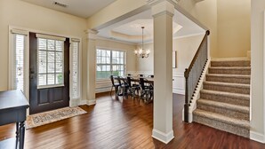 A spacious living area with hardwood floors, a dining table, and a staircase. - 5br/3ba, sleeps 12! Newly renovated w/ media room! (Lawrenceville)