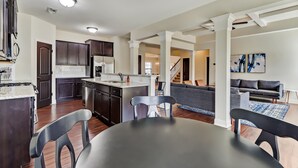 A modern kitchen with dark wood cabinets, a central island, and a dining area with a table and chairs. - 5br/3ba, sleeps 12! Newly renovated w/ media room! (Lawrenceville)